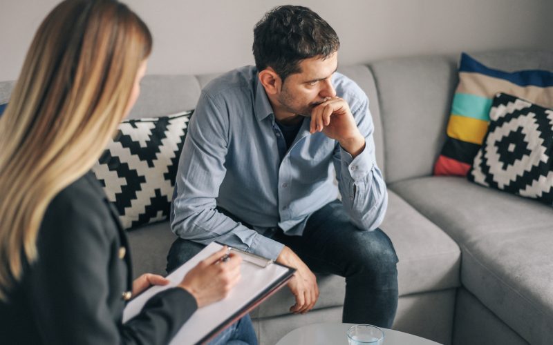 Young man, alcoholic, talking to female therapist about his problems, on  therapy session