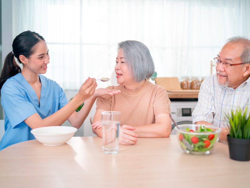 nurse-or-doctor-who-work-as-homecare-staff-help-to-serve-a-spoon-of-mush-rice-to-senior-woman.jpg